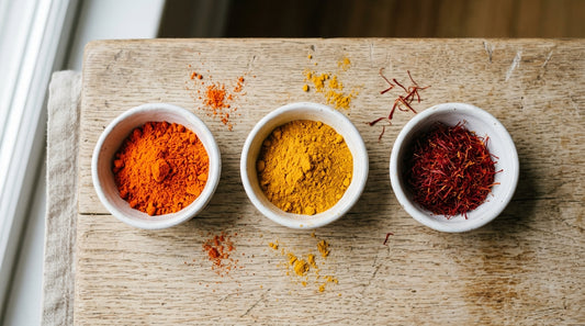 Colorau, cúrcuma e açafrão verdadeiro lado a lado em tigelas de cerâmica, mostrando a diferença de cor entre os três temperos